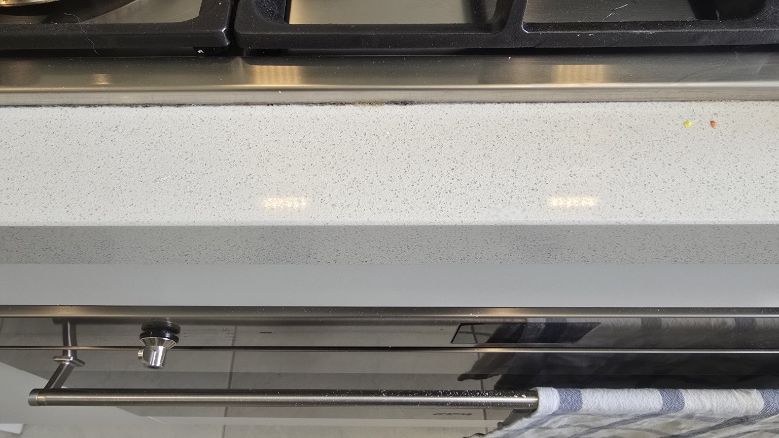 Repaired front edge of the same pale speckled stone benchtop in front of the cooktop